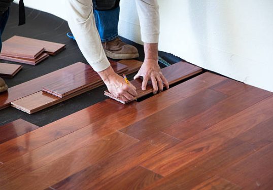 A worker installing hardwood floor in an American upscale home.A worker installing hardwood floor in an American upscale home.