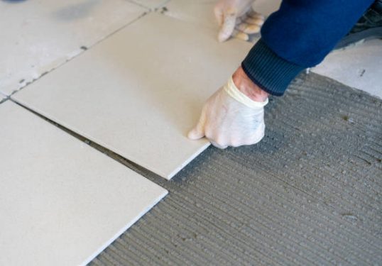 Lay ceramic Tiles. Troweling mortar onto a concrete floor in preparation for laying white floor tile