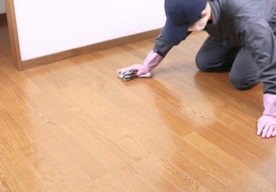 A worker cleaning and waxing a floor.